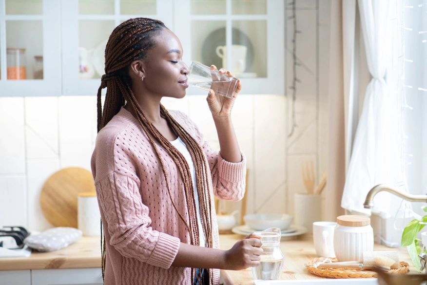 woman enjoying fresh glass of water in kitchen img